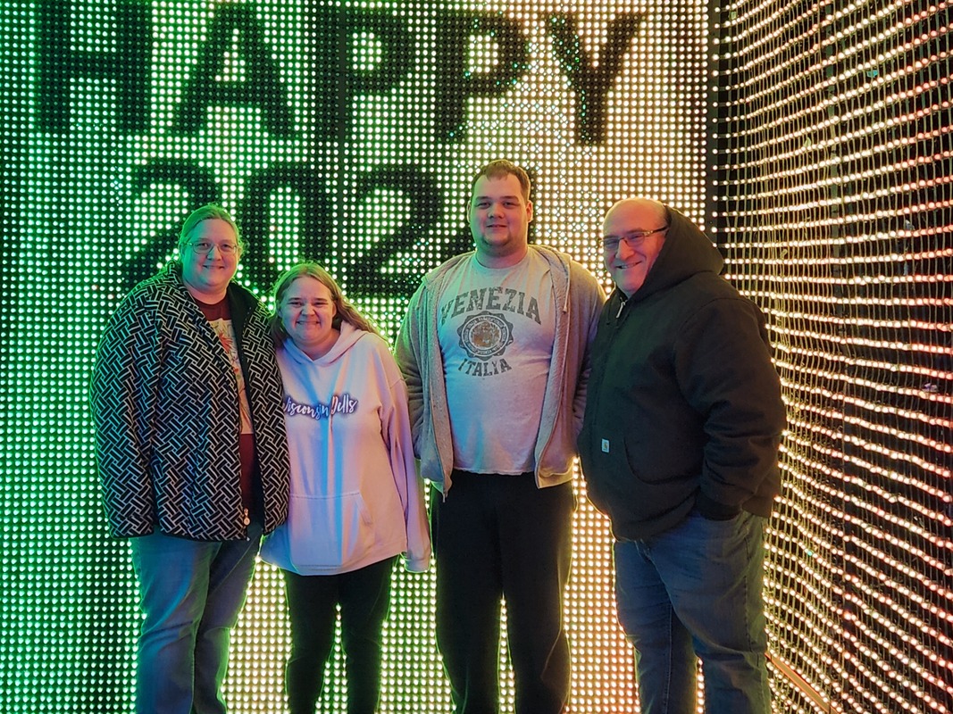 Family posing in front of the Happy 2024 display on New Year's Eve